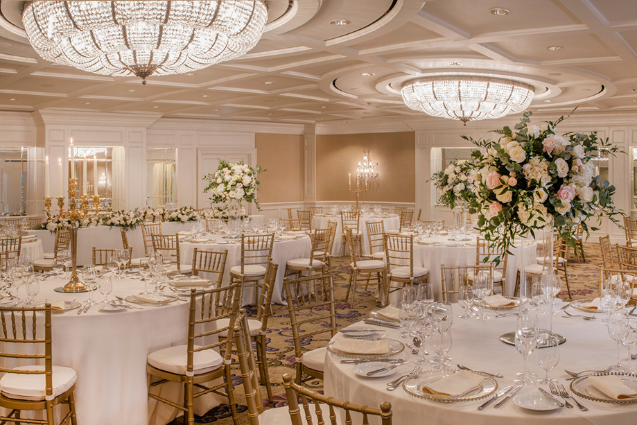 Ballroom wedding meal set up with flowers and gold accents