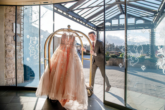 Staff member pushes trolley with dress hanging