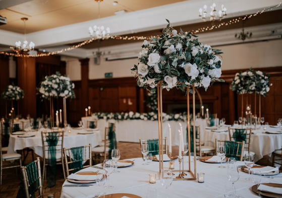 Wedding breakfast setup with green and white floral centrepiece